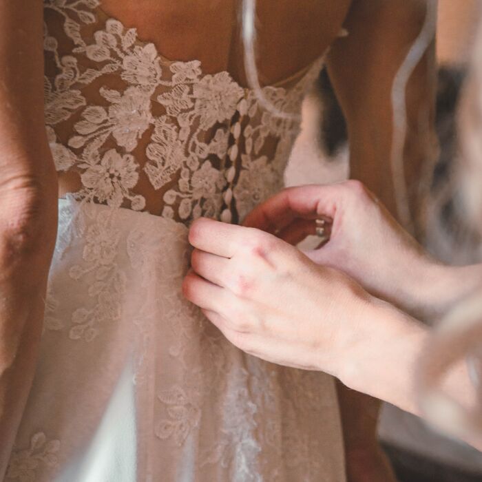 Anziehen des Brautkleides mit schönem Rückenausschnitt während des Getting Ready's für eine Hochzeit im Schlosshotel Schkopau