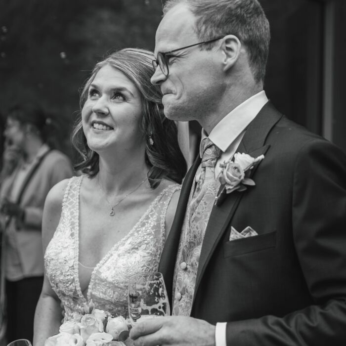 ein Brautpaar nach der Trauung, das sich über die Seifenblasen und seine Gäste freut