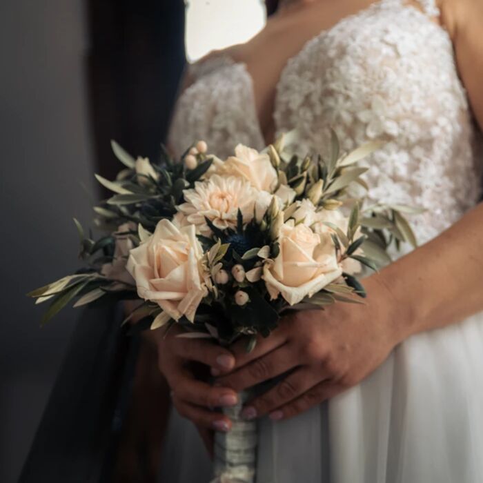 Brautstrauß mit weißen Dahlien, weißen Rosen und Olivenzweige, gehalten von der Braut