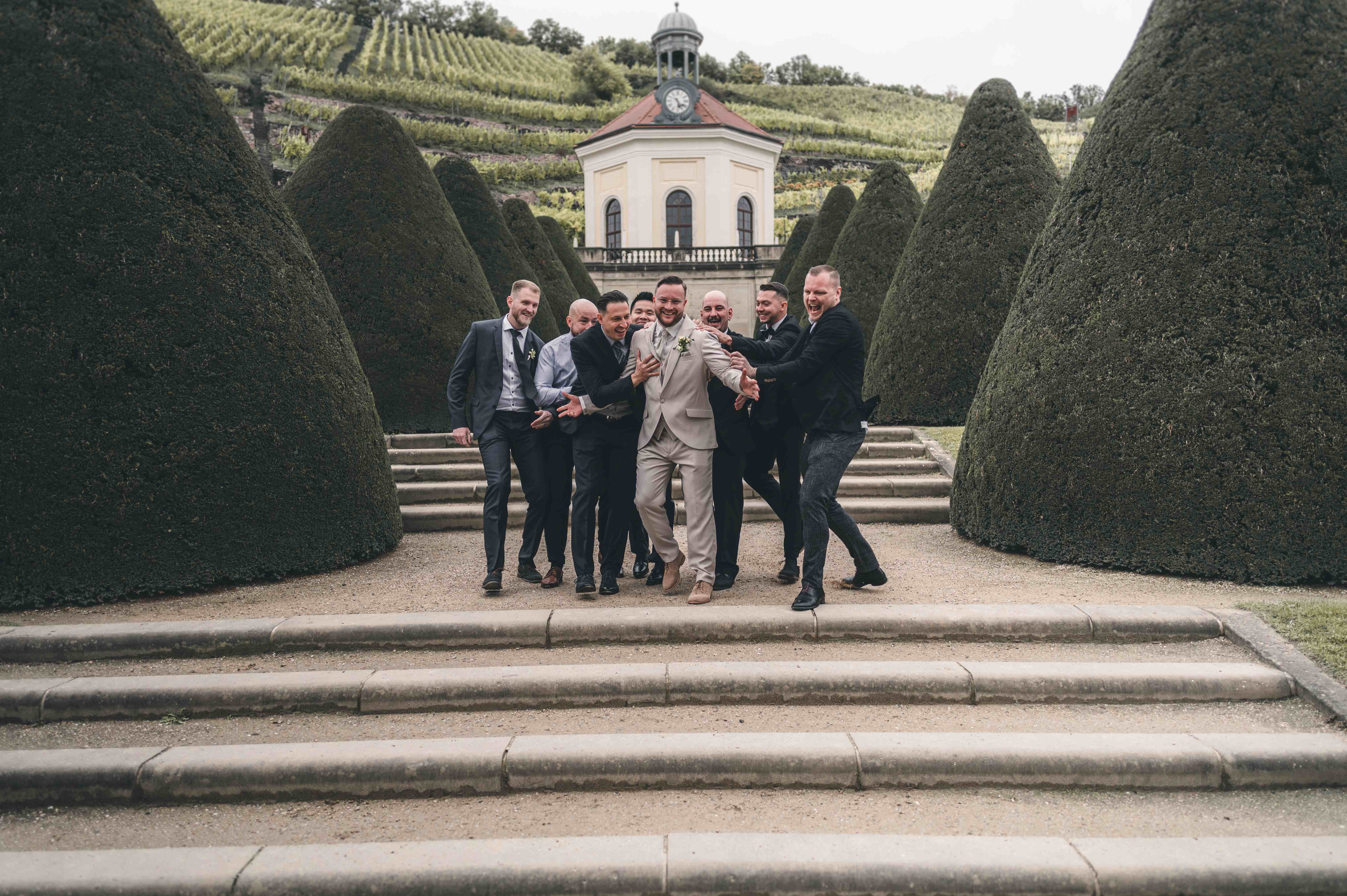 Locker aufgenommenes Gruppenfoto des Bräutigams mit seinen Freunden vor Schloss Wackerbarth in Radebeul – Hochzeitsreportage Sachsen