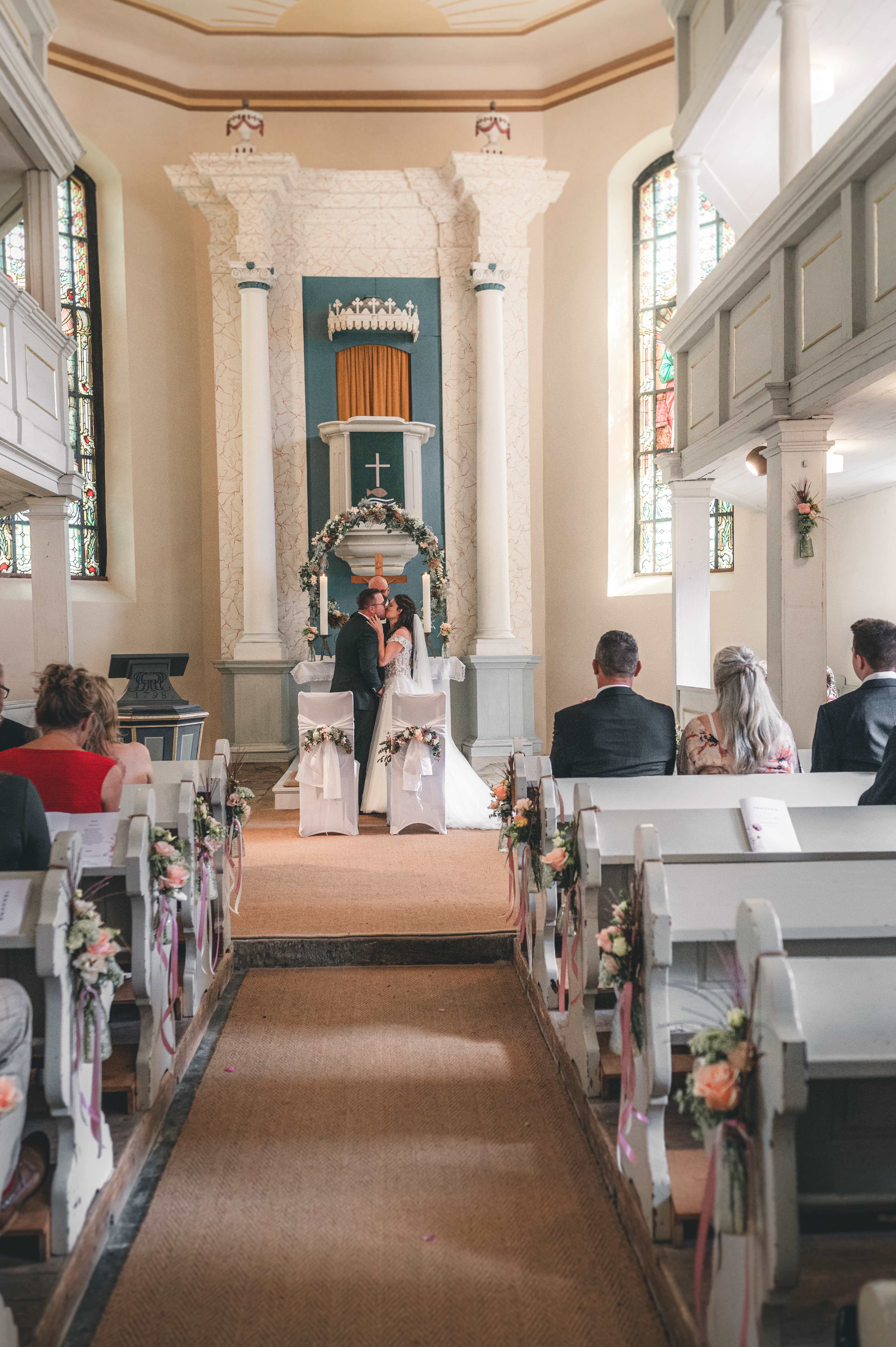 Das frisch vermählte Brautpaar küsst sich innig nach dem Segen vor dem Altar der historischen Kirche in Leisnig.