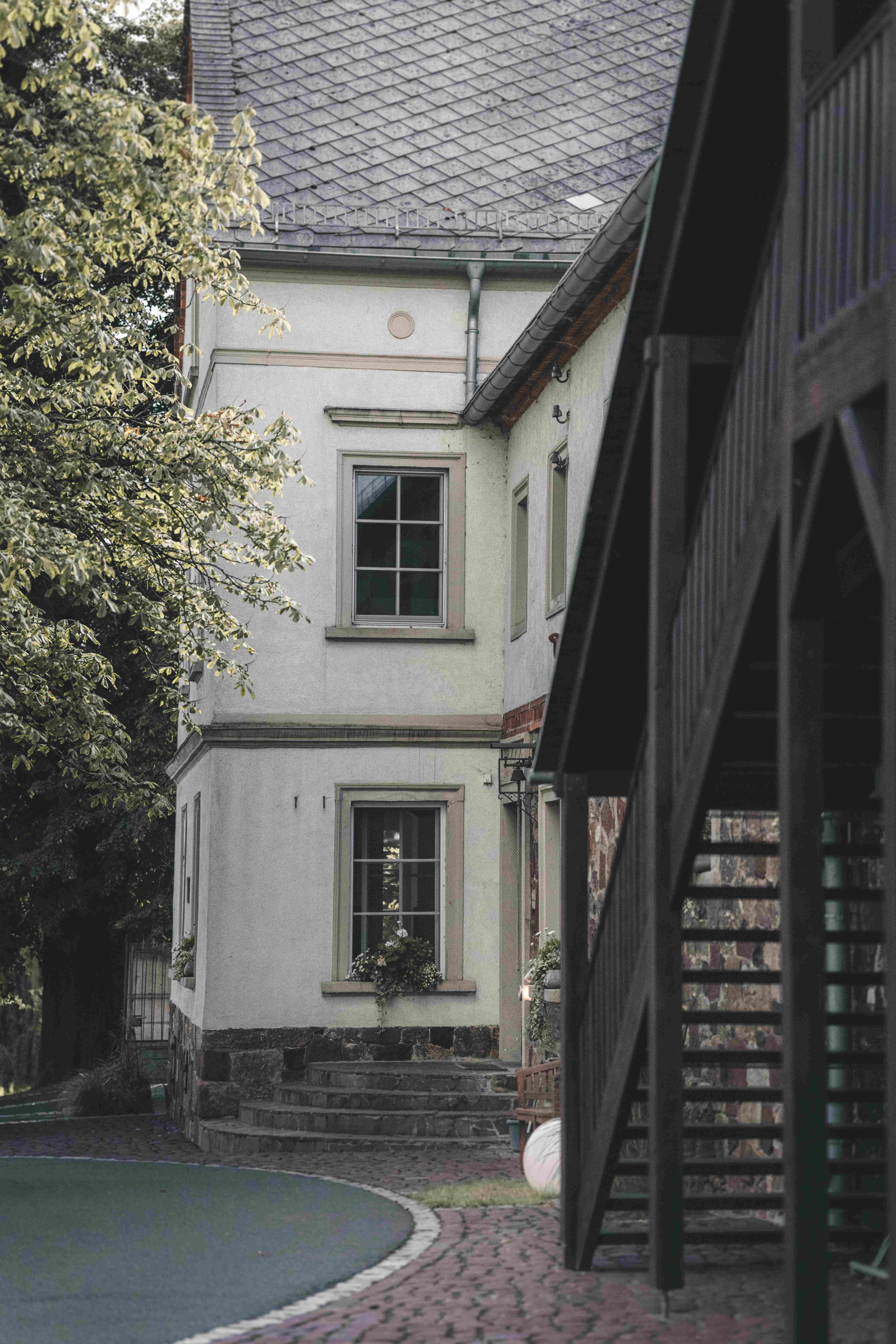 Eine stimmungsvolle Ansicht des historischen Hofguts Munz in Leisnig mit alten Steinstufen, Sprossenfenstern und einer rustikalen Holztreppe.