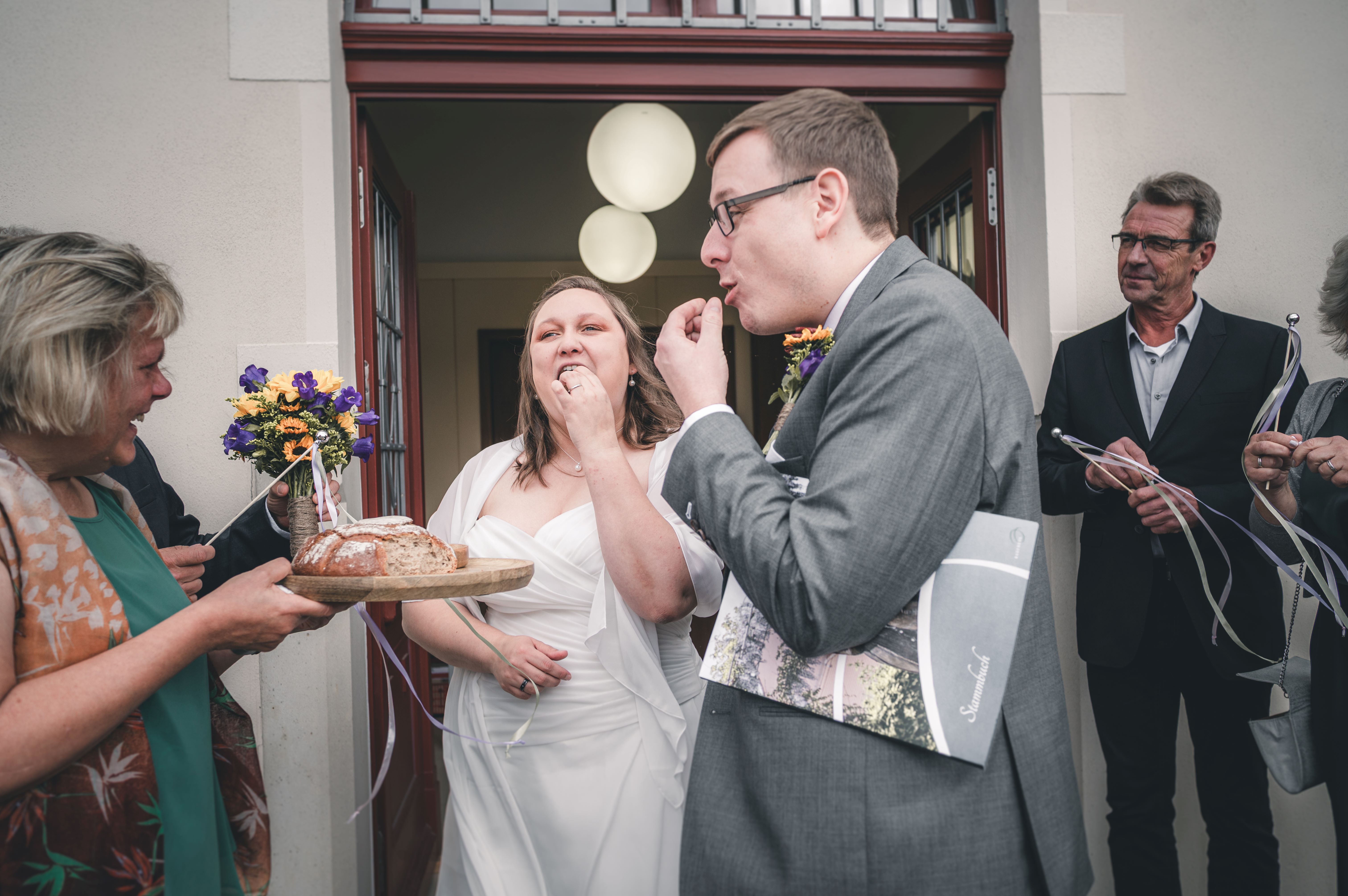 Das Brautpaar probiert nach dem Auszug in Radebeul bei Dresden das traditionelle Hochzeitsbrot mit Salz, das ihnen von Gästen gereicht wird.