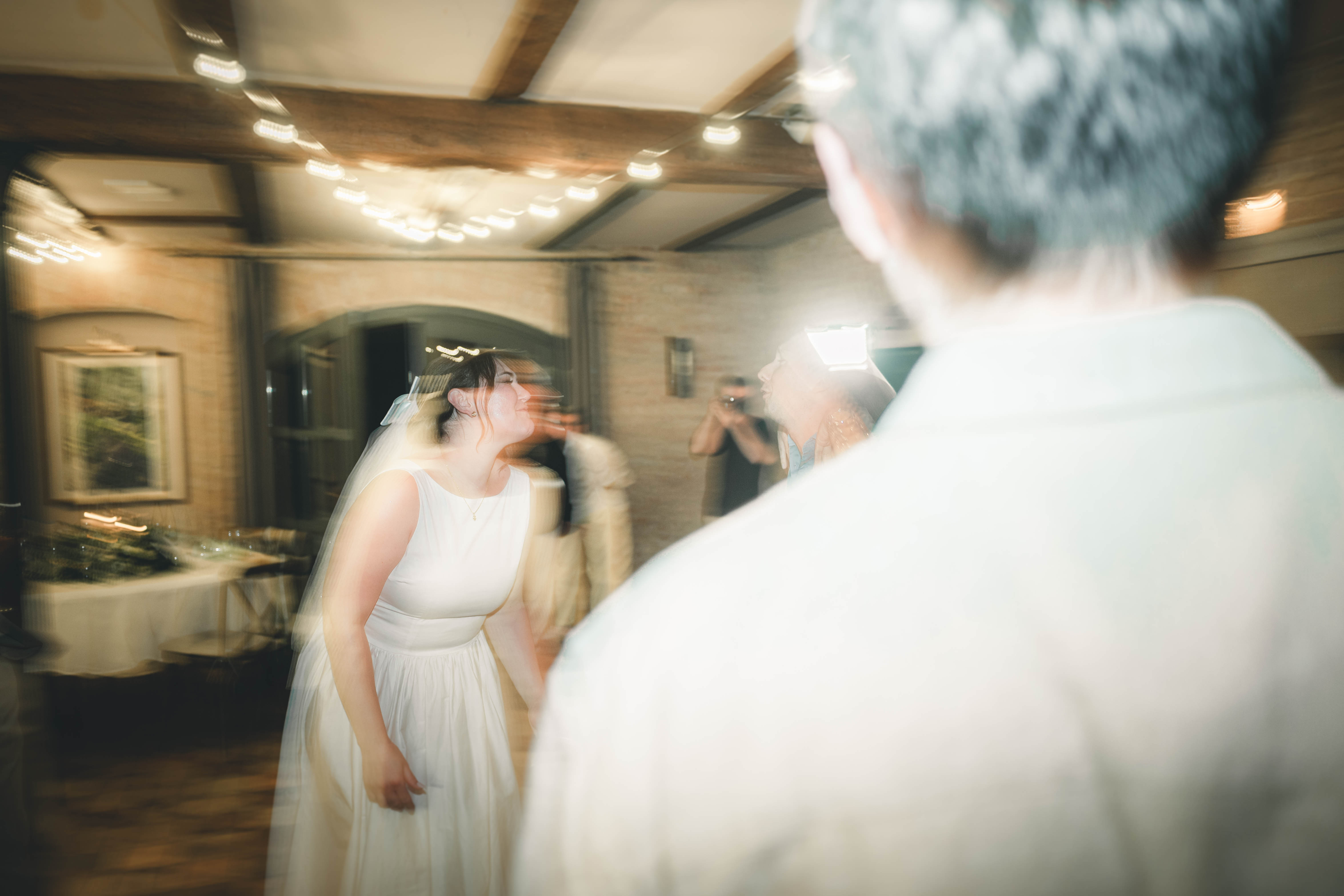 Die Braut im weißen Kleid tanzt mit Schwung und Freude unter hängenden Lichterketten im Saal des Magdalenenguts Erfurt.