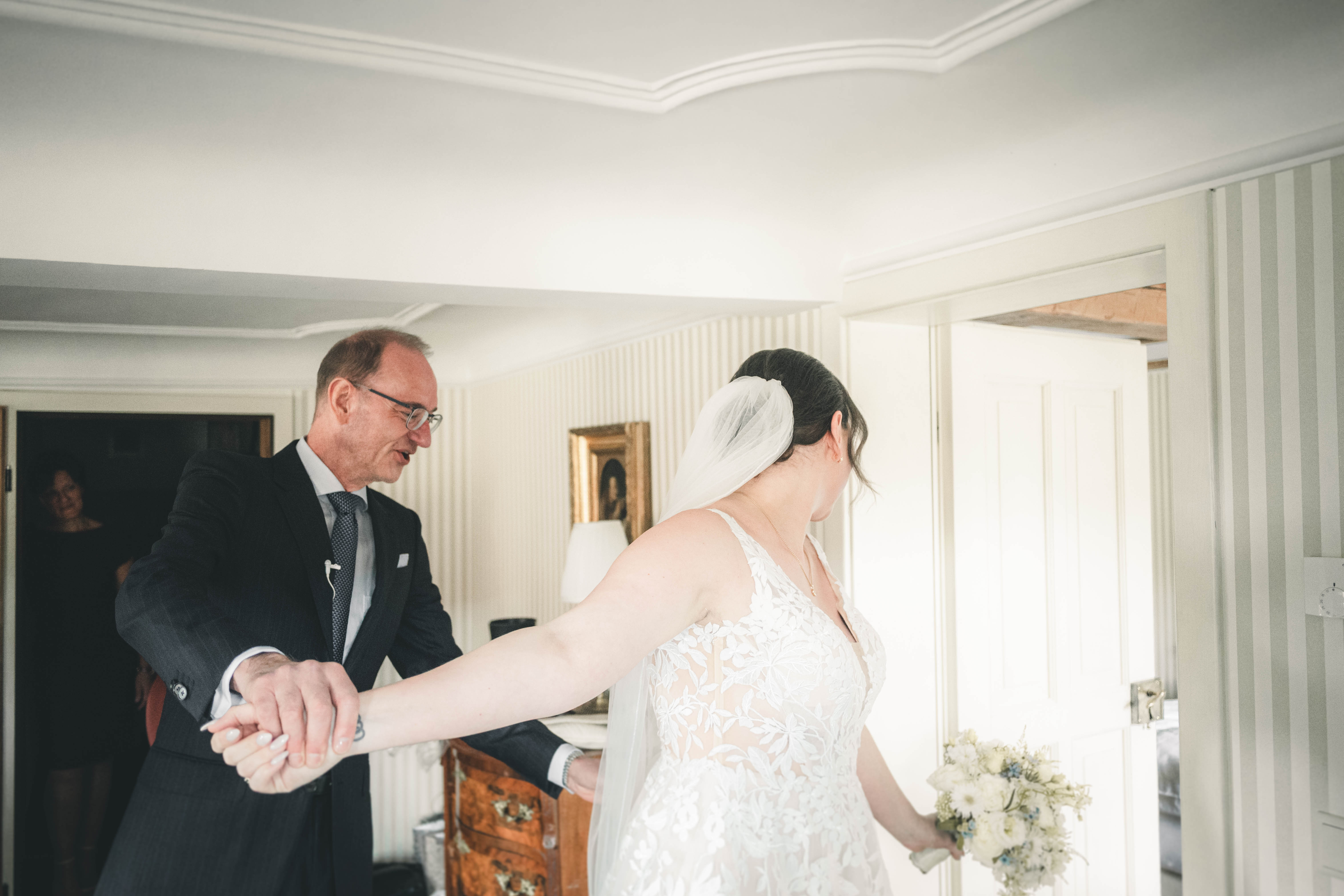 Die Braut dreht sich an der Hand ihres sichtlich berührten Vaters im hellen Salon des Magdalenenguts Erfurt und präsentiert ihr Hochzeitskleid.