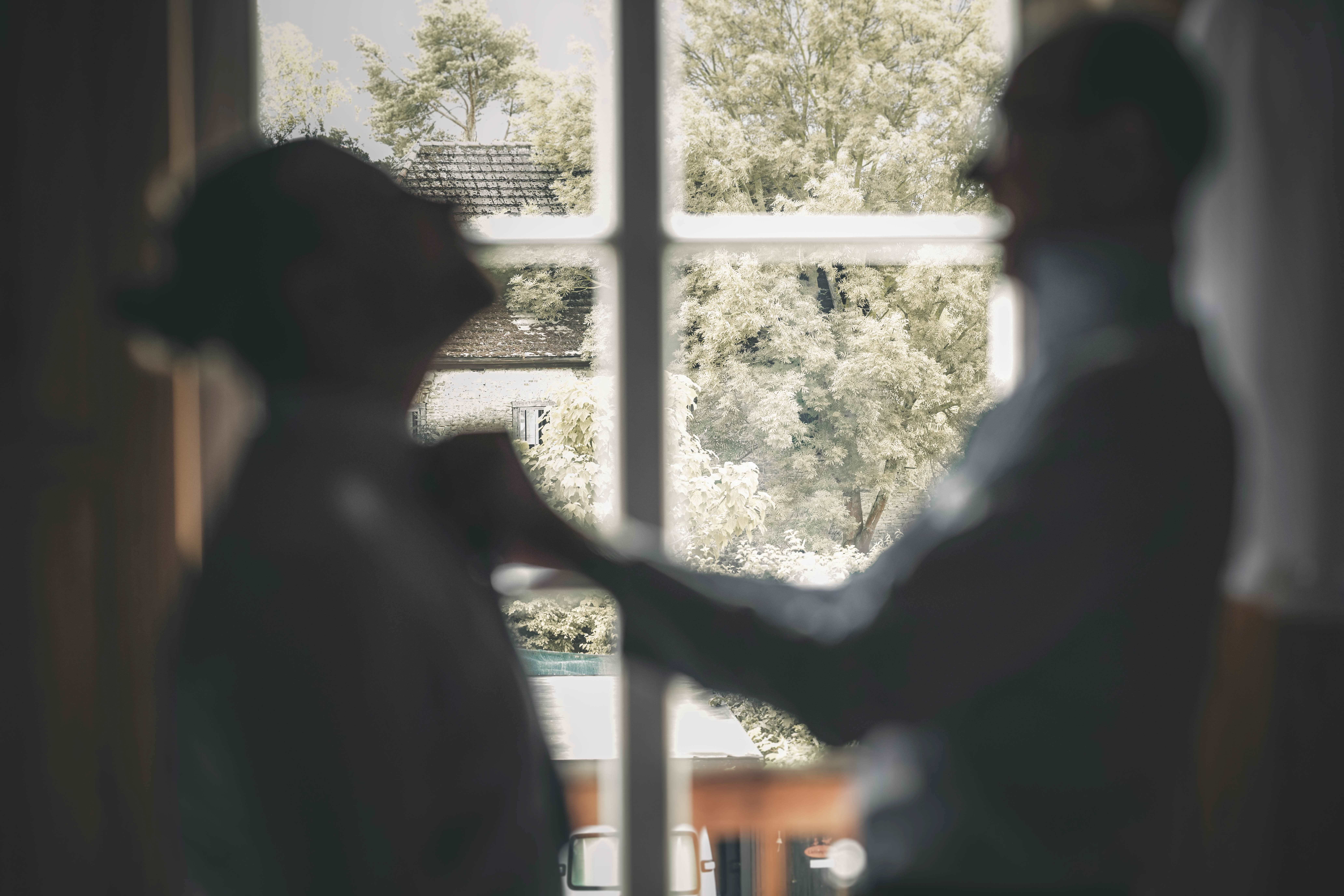 Silhouette zweier lachender Männer am Sprossenfenster des Magdalenenguts Erfurt mit Blick in die grüne Natur.
