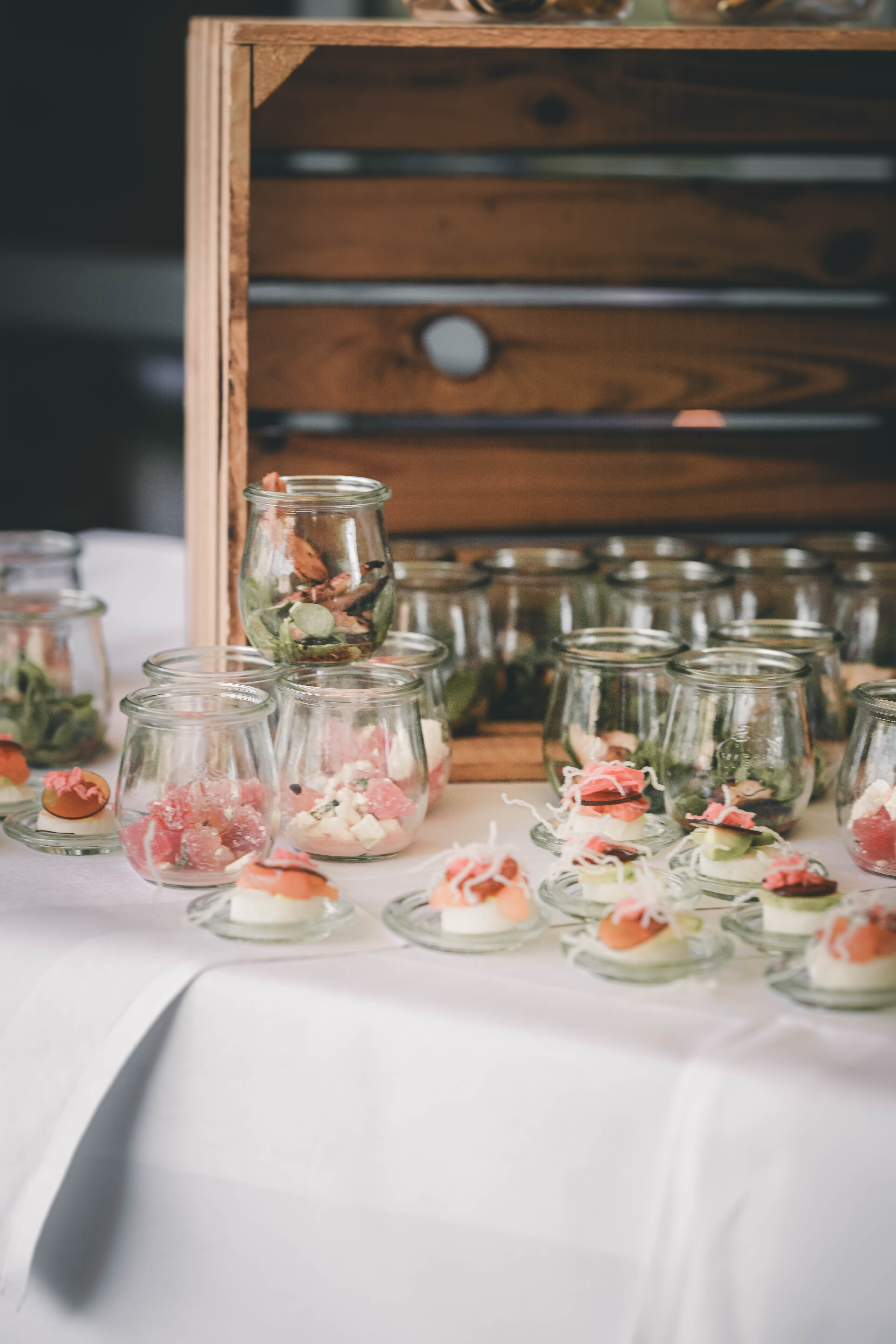 Arrangement aus verschiedenen Fingerfood-Gläschen und feinen Häppchen auf einer weißen Tischdecke im Magdalenengut Erfurt.