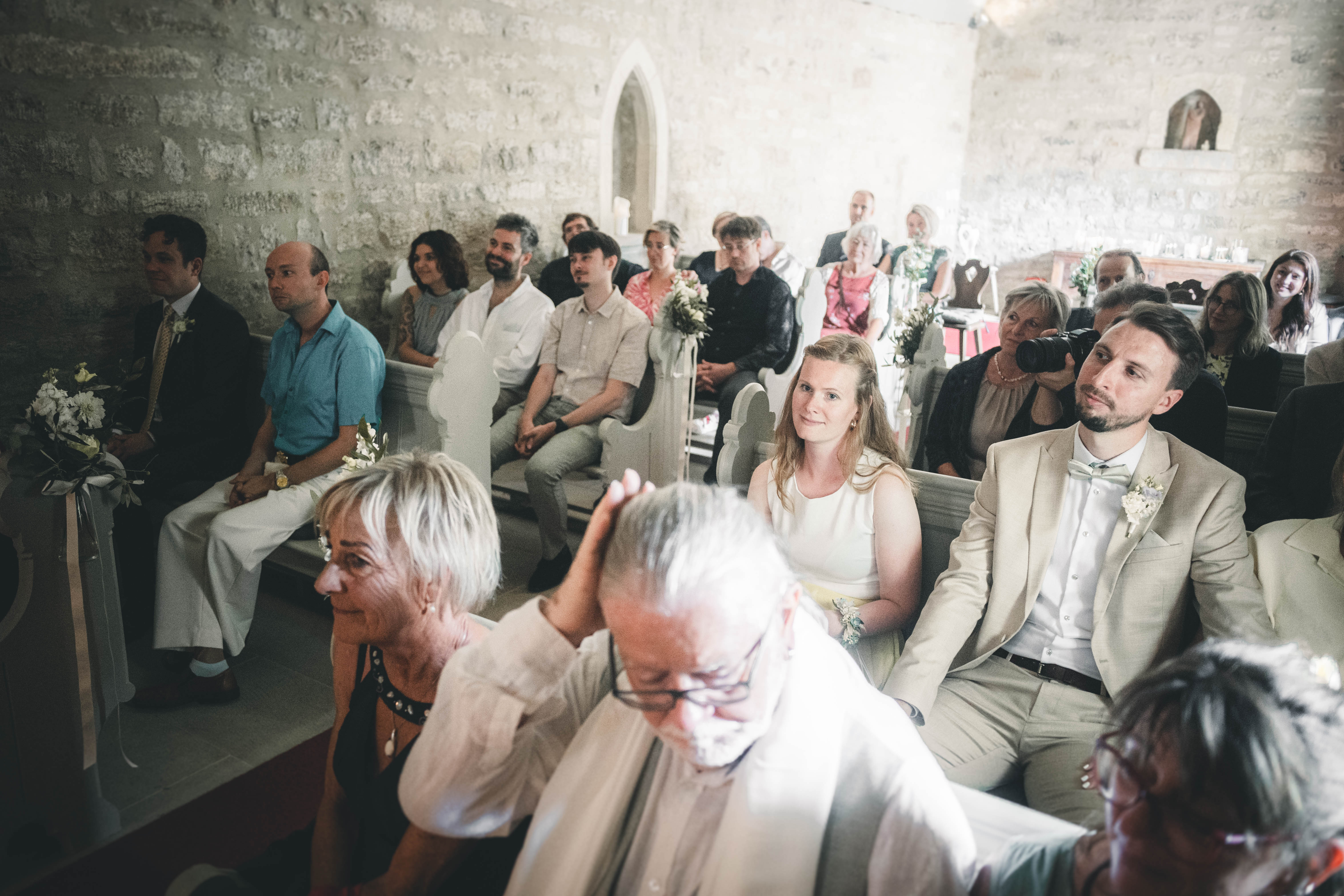Die Hochzeitsgesellschaft sitzt in den Holzbänken der hellen Steinkapelle im Magdalenengut Erfurt und verfolgt die Trauzeremonie.