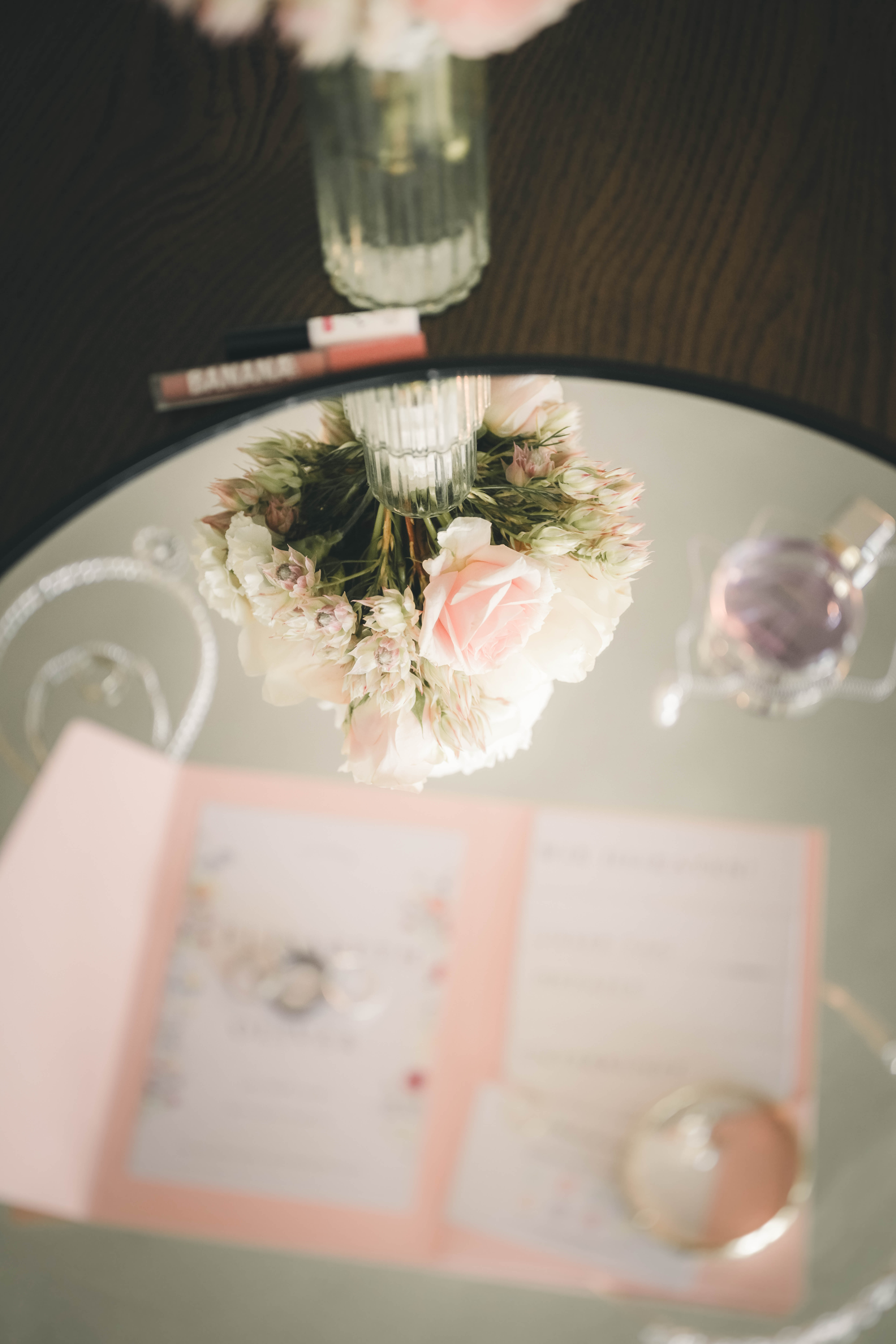 Eine kreative Draufsicht im Spiegel, die den zarten Blumenstrauß, Schmuck und die Hochzeitspapeterie kunstvoll reflektiert.