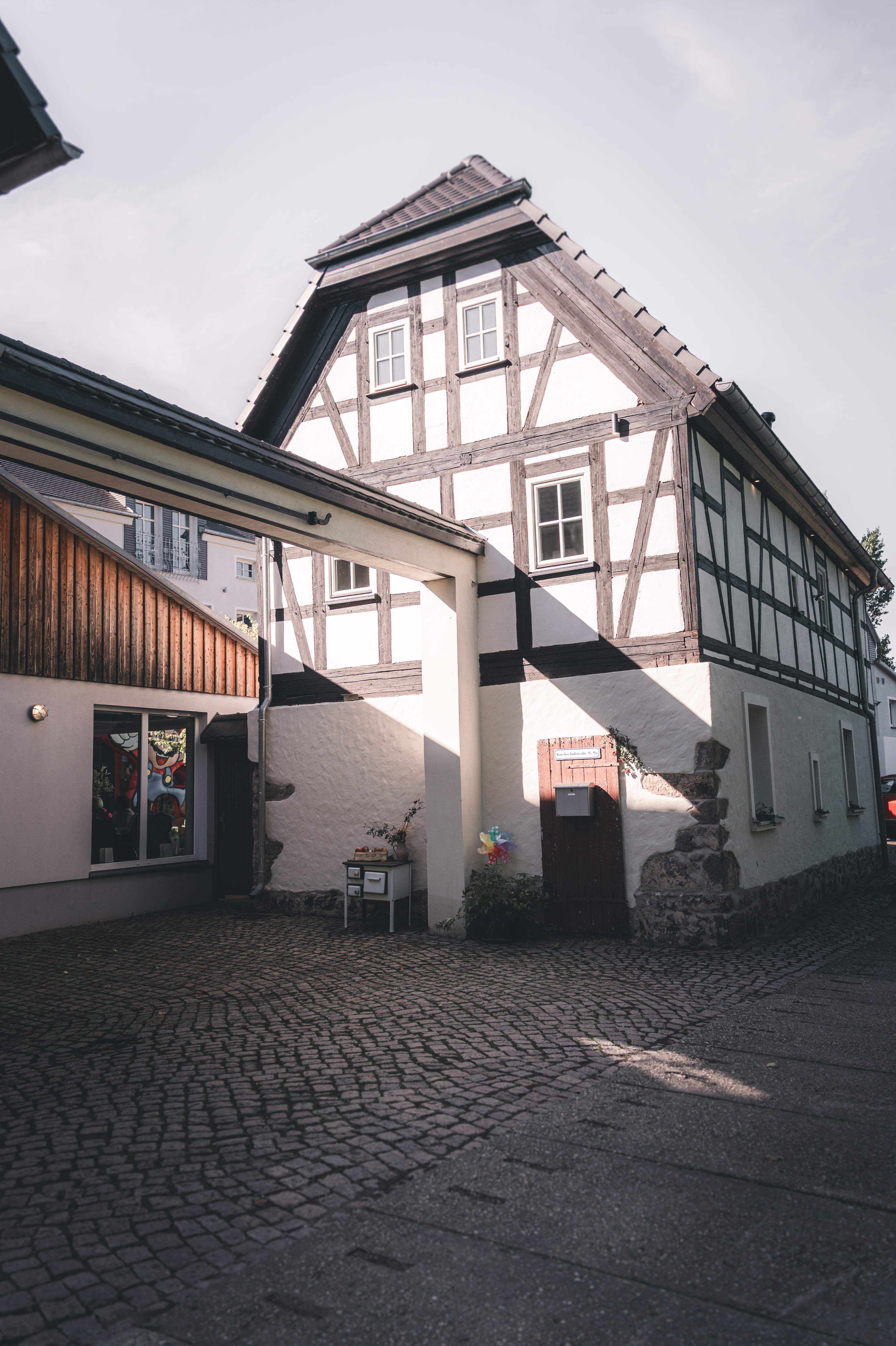 Die liebevoll restaurierte Fachwerk-Fassade des Erlebnishofs Pleißental in Fraureuth unter blauem Sommerhimmel.