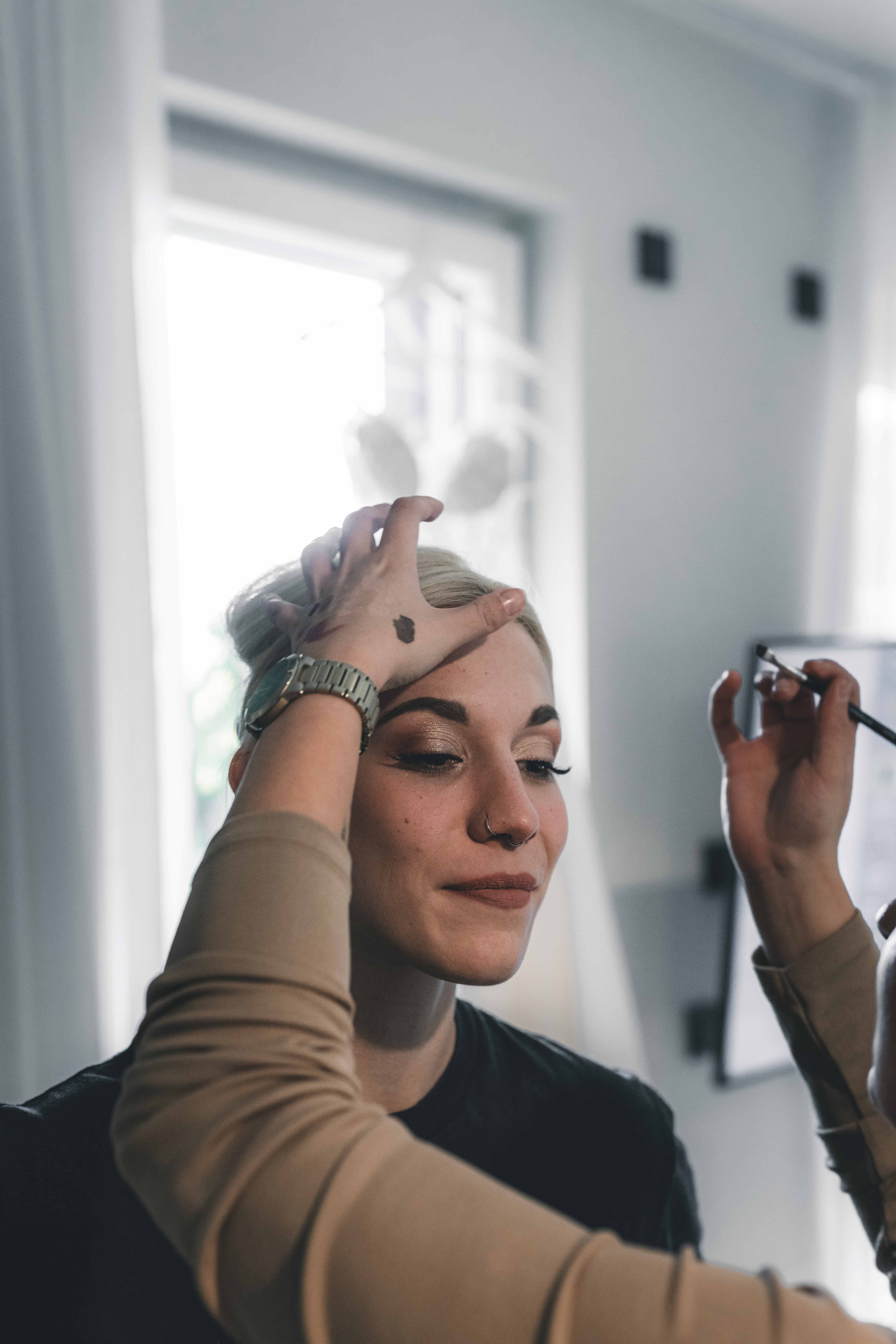 Nahaufnahme einer Braut beim Getting Ready für ihre Hochzeit auf Schloss Wackerbarth, während die Visagistin ihr feines Augen-Make-up aufträgt.