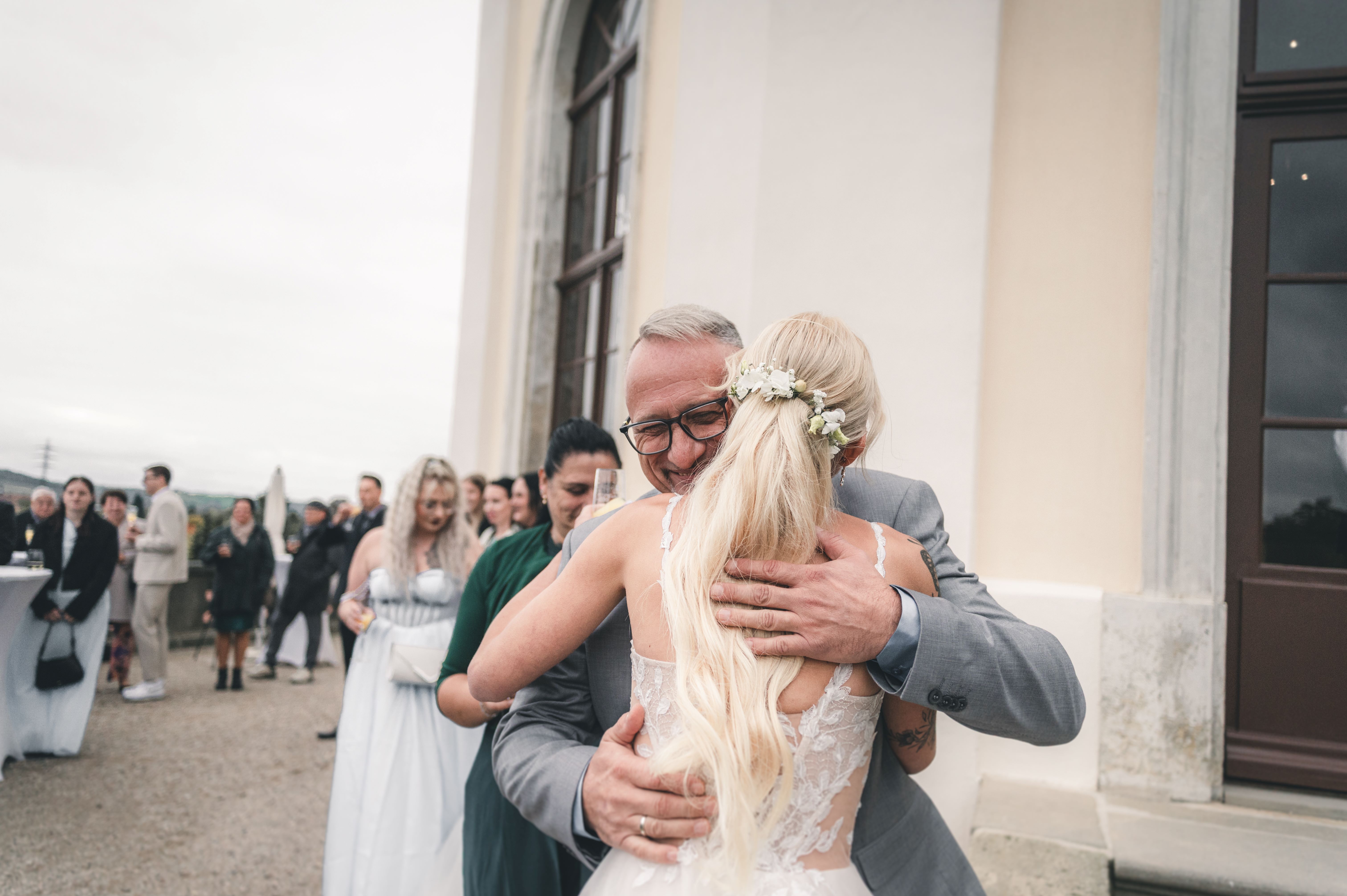 Der sichtlich glückliche Brautvater nimmt seine Tochter auf der Schlossterrasse fest und gerührt in den Arm, um ihr zur Hochzeit zu gratulieren.