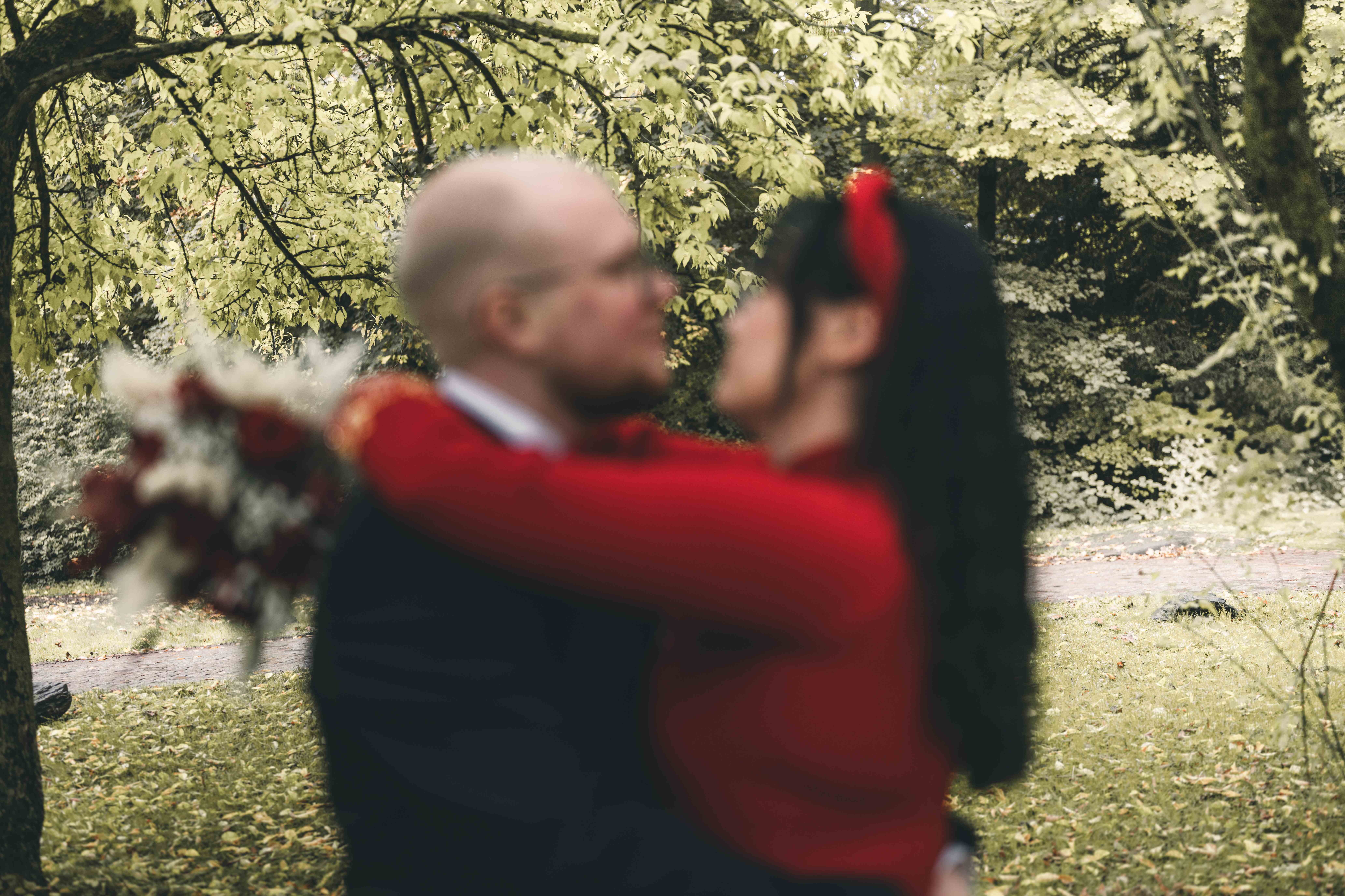 Ein kreatives Hochzeitsfoto mit gewollter Bewegungsunschärfe (Motion Blur) zeigt das Brautpaar beim Kuss im herbstlichen Wald.