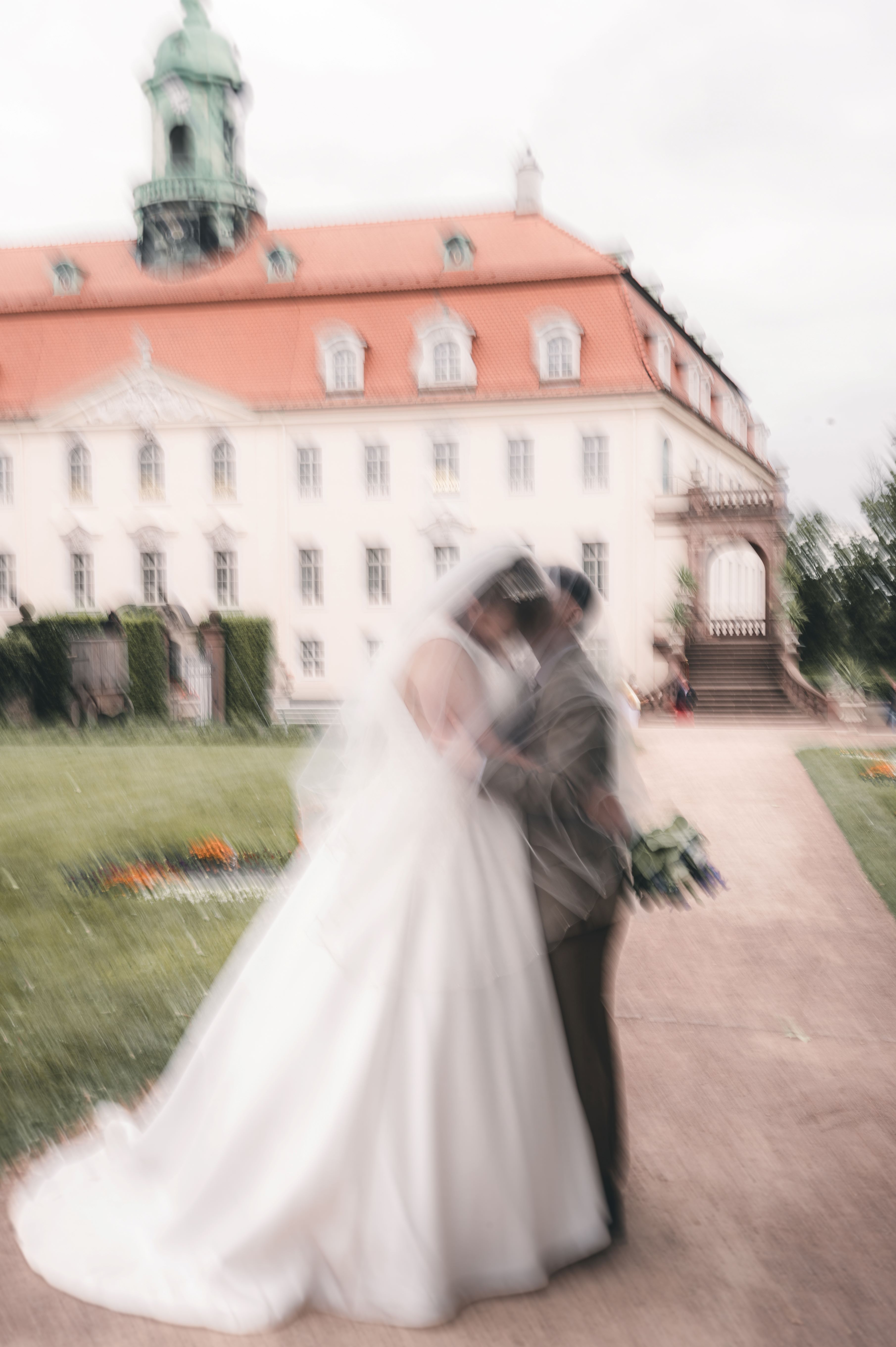 Eine kreative Hochzeitsfotografie mit Bewegungsunschärfe (Motion Blur) zeigt das Brautpaar beim innigen Kuss vor der Schlosskulisse bei Chemnitz.