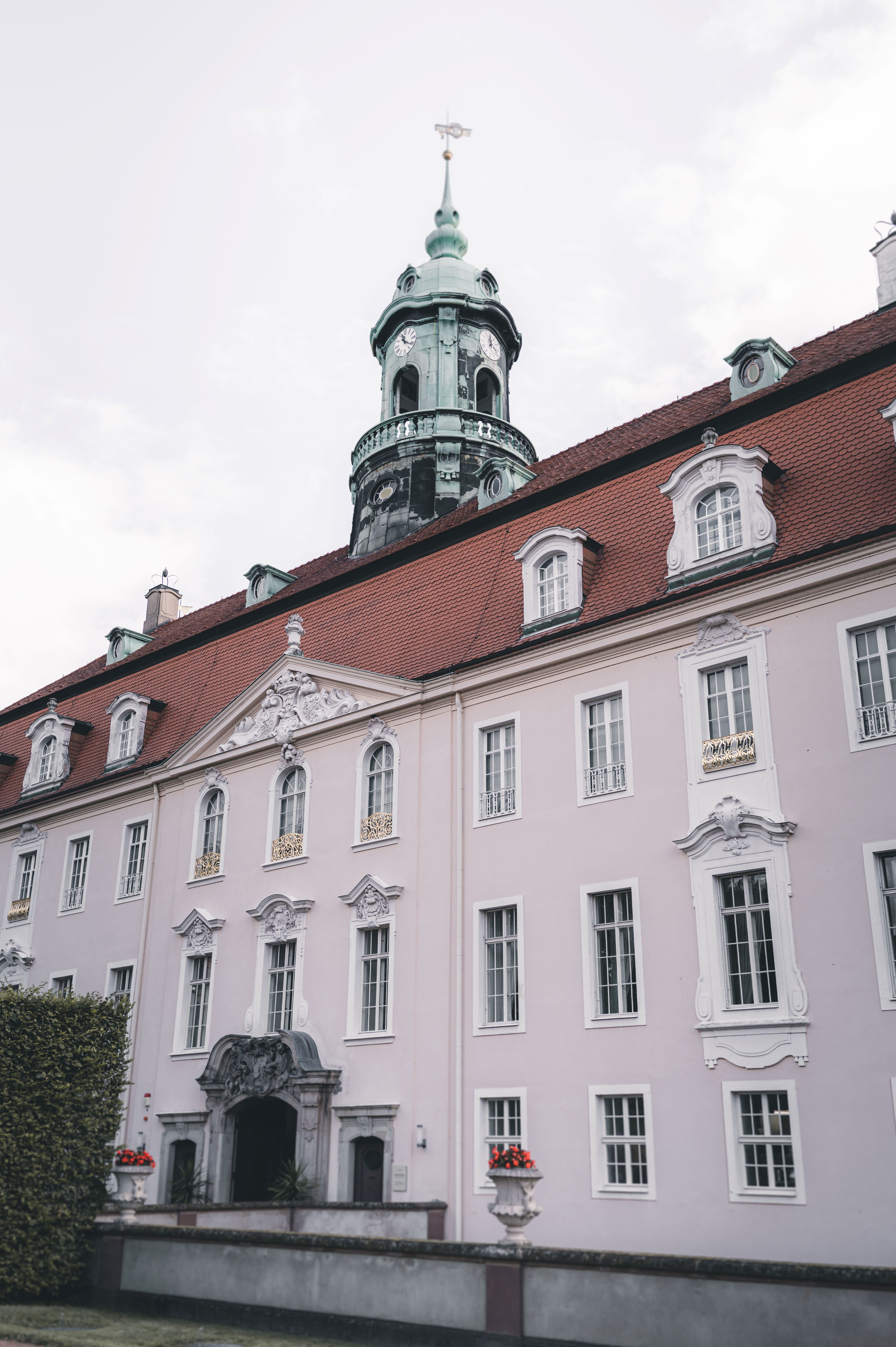 Detailaufnahme der rosafarbenen Fassade und des markanten grünen Turms von Schloss Lichtenwalde für ein Hochzeitsportfolio in Sachsen.
