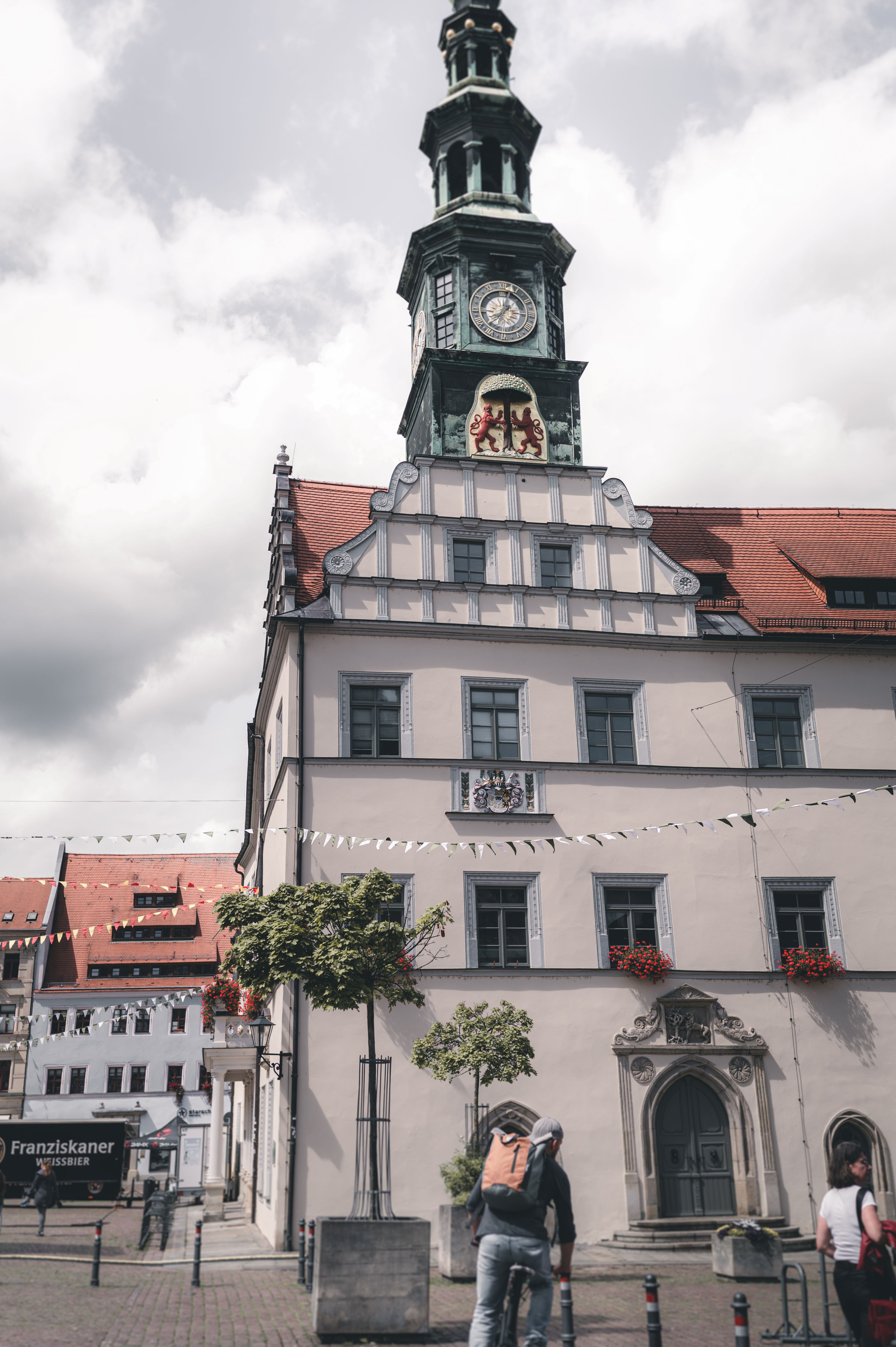 Die imposante Außenfassade des historischen Rathauses in Pirna mit seinem hohen Uhrenturm unter bewölktem Himmel im Elbsandsteingebirge.