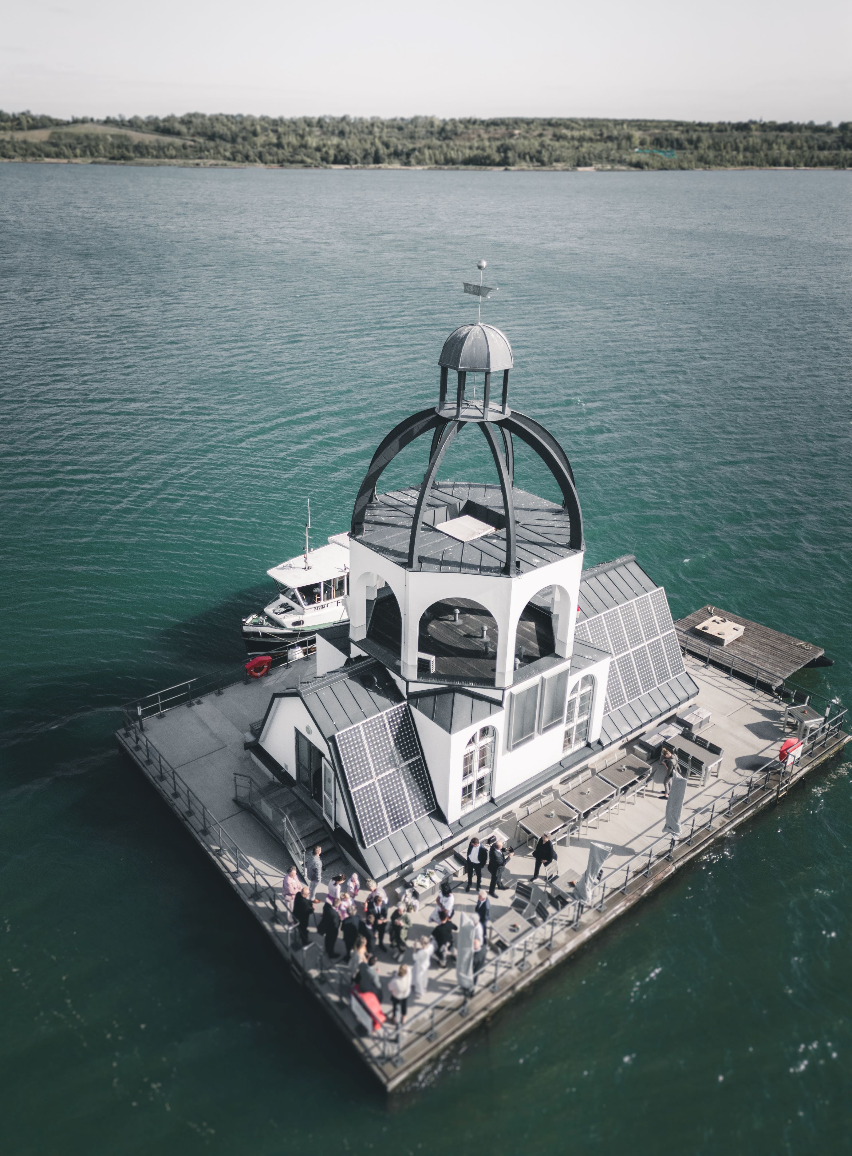 Eine beeindruckende Drohnen-Luftaufnahme der schwimmenden Hochzeitslocation VINETA auf dem türkisfarbenen Störmthaler See bei Leipzig.