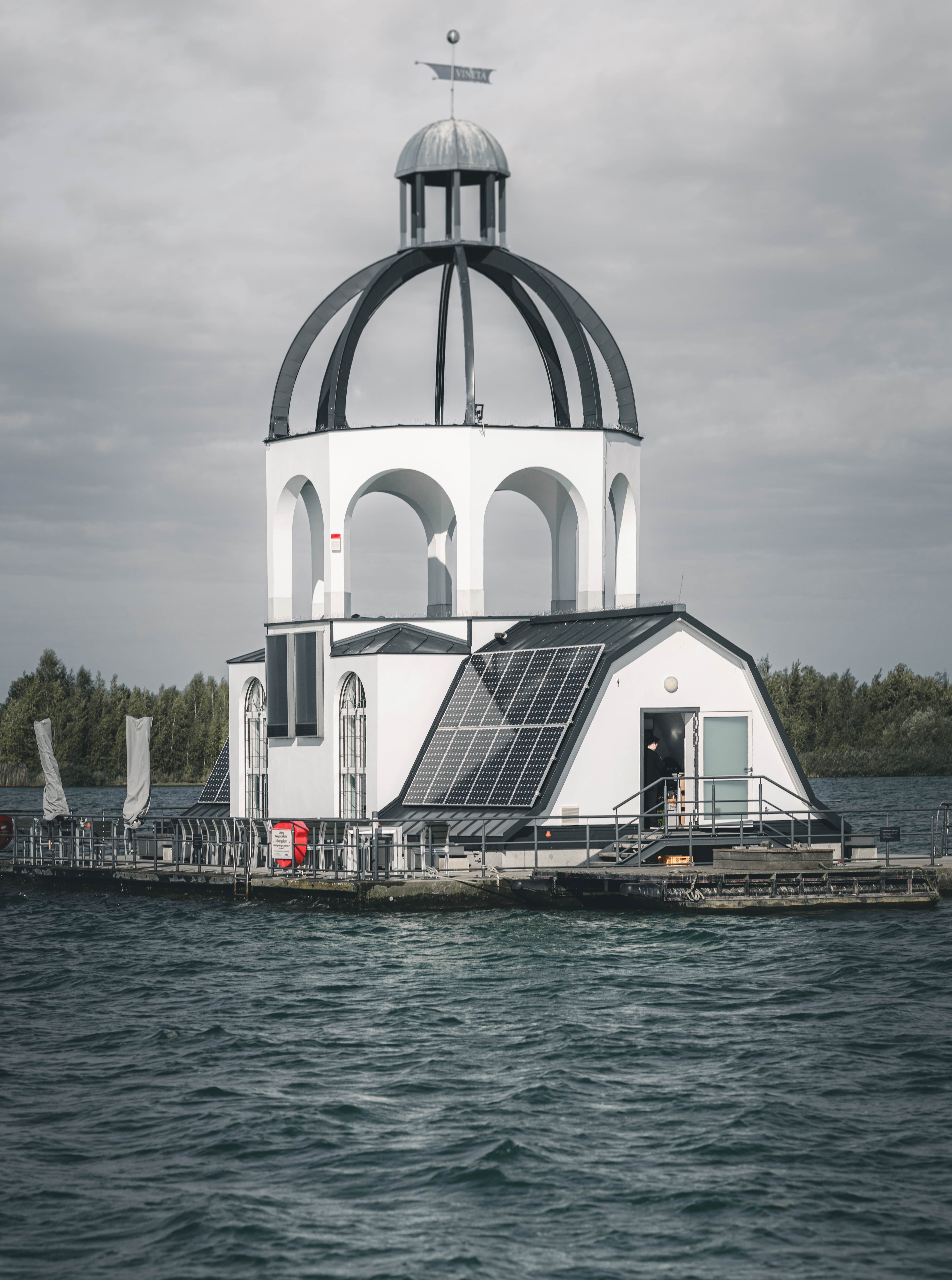 Die markante weiße Architektur der schwimmenden Kirche VINETA mit Solarpaneelen mitten auf dem welligen Störmthaler See.